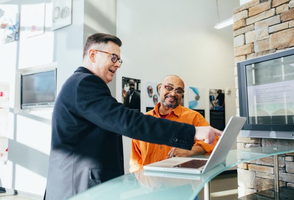 Afbeelding - team werkt samen voor laptop, man wijst iets aan