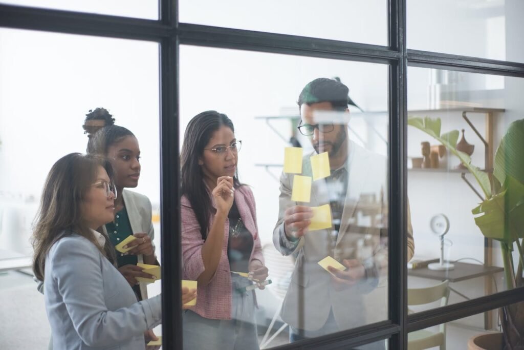 4 personen op kantoor kijken naar post-its tegen uur